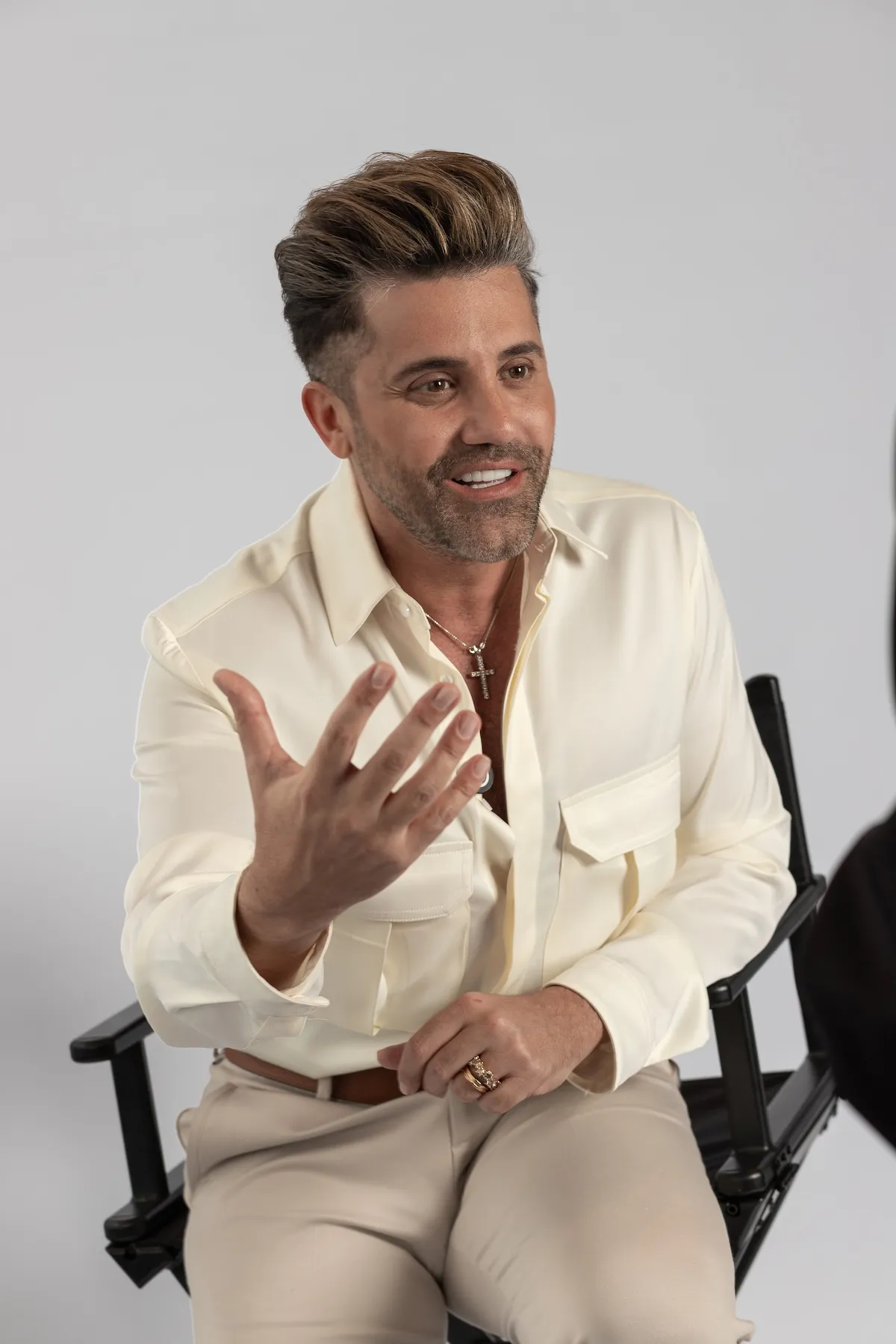Gabriel Samra sentado, vestido de crema, explicando algo con la mano abierta
