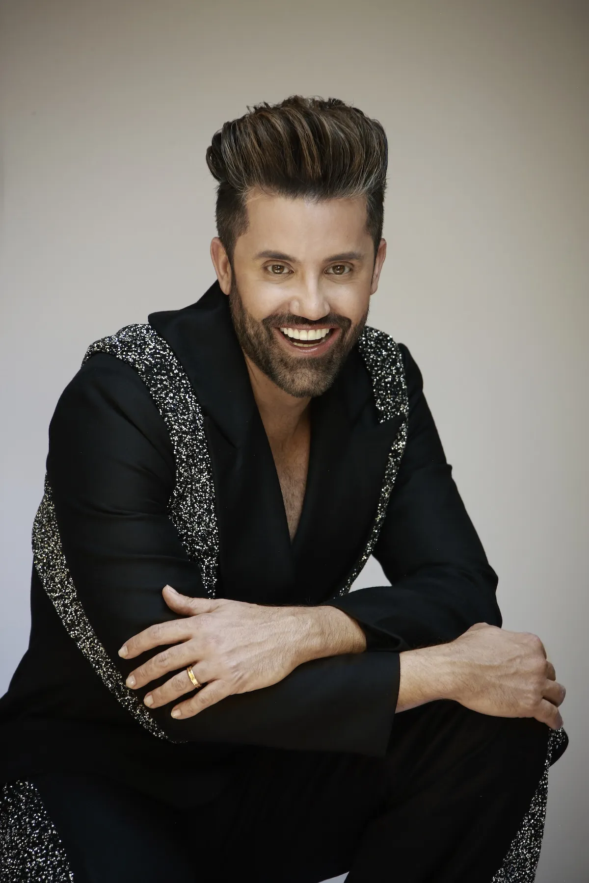 Retrato de Gabriel Samra sonriendo, con las manos cruzadas sobre las rodillas